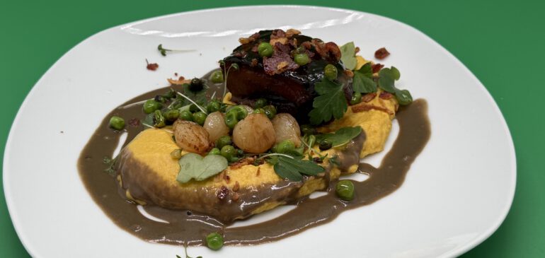 Hohe Rippe vom Wollschwein auf Maispüree mit Wildkräutern und Silberzwiebeln